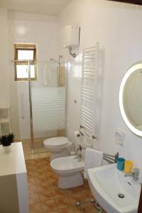 La salle de bains est pourvue de toilettes, d'un lavabo et d'un miroir. dans l'établissement Abate Gimma Apartment, à Bari