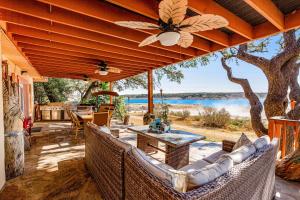 an outdoor patio with couches and tables and a view of the water at Lakeside House in Austin