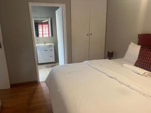 a bedroom with a white bed and a sink at Sun & Night in Empangeni