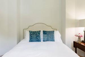 um quarto com uma cama branca e almofadas azuis em The Lodge at Willow Camp em Stinson Beach