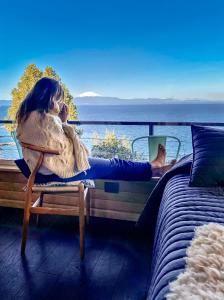 a woman sitting on a bench talking on a cell phone at Los laureles in Frutillar