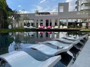 uma piscina com cadeiras brancas em frente a um edifício em Ipoh Luxurious Homestay by Comfort Home em Ipoh