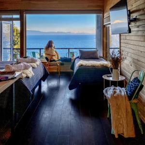 una mujer sentada en una habitación con vistas al océano en "Los laureles" vista al lago, en Frutillar