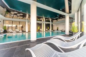 una piscina con sedie bianche in un edificio di Apartament Westin House 303 a Kołobrzeg