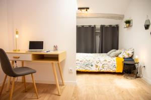 a bedroom with a desk and a bed with a computer at DUPLEX COCOON - 10 MIN DE BLAYE - 20 MIN CNPE - WiFi - TV HD in Saint-Seurin-de-Cursac