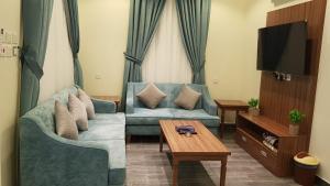 - un salon avec un canapé bleu et une table dans l'établissement شاليهات التميز الراقي, à Al Hada