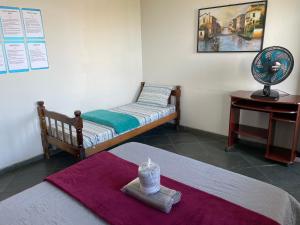a room with two beds and a table with a fan at Hope Hostel Guarapari in Guarapari