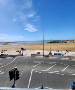 an empty street in front of a beach with people at Imperial House Sea View Margate in Kent
