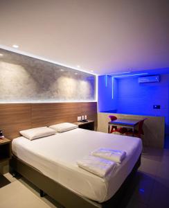 a bedroom with a large white bed with blue lighting at Link Motel in Cabedelo