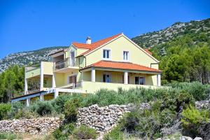 una casa amarilla con techo naranja en una colina en Villa Marin - 4 apartments en Zavala