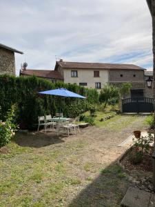 a table and chairs with an umbrella in a yard at Chez Élise et Jean Yves in Job