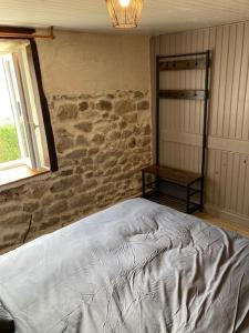 a bedroom with a bed and a stone wall at Chez Élise et Jean Yves in Job
