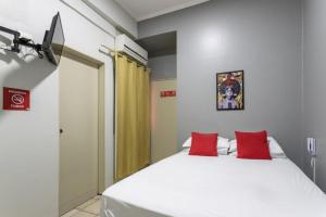 a bedroom with a large white bed with red pillows at Hotel Apiacas in Ribeirão Preto