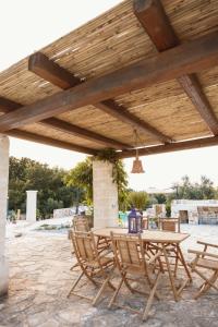 a patio with a table and chairs under a woodenilion at Trulli Santa Maria Odegitria Relais in Ostuni
