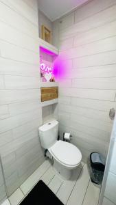 a white bathroom with a toilet and a neon sign at Spazen30 in Nîmes