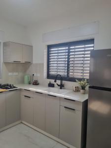 a kitchen with white cabinets and a sink and a window at עלות השחר - יחידת אירוח בצפון in Qiryat Shemona