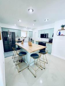 a kitchen with a wooden table and four bar stools at Designer Pool & Family Dream Home in Hollywood