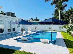 a swimming pool with two blue umbrellas and two chairs and a pool at Designer Pool & Family Dream Home in Hollywood