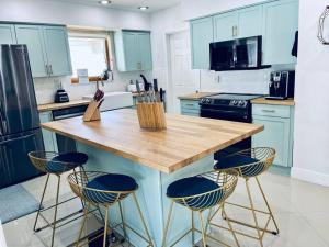 a kitchen with blue cabinets and a wooden island with stools at Designer Pool & Family Dream Home in Hollywood +56 photos