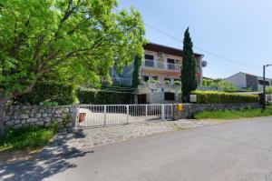 una cerca frente a una casa con un árbol en Apartments and Room Luka, en Klenovica