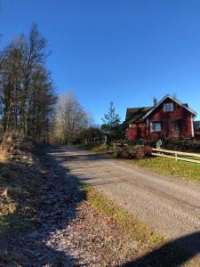 einen Feldweg neben einem roten Haus und einem Zaun in der Unterkunft Bokskog, sjö, MTB, Gekås Varberg in Rolfstorp