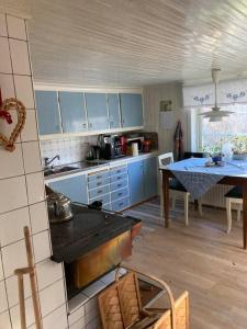 a kitchen with blue cabinets and a table in it at Bokskog, sjö, MTB, Gekås Varberg in Rolfstorp