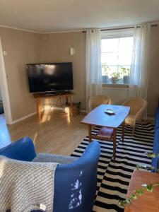 uma sala de estar com uma televisão e uma mesa e cadeiras em Bokskog, sjö, MTB, Gekås Varberg em Rolfstorp