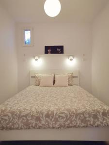 een witte slaapkamer met een groot bed met 2 kussens bij Small house with private park and yard in Terrugem