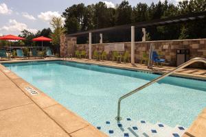 a swimming pool at a resort with chairs and tables at Home2 Suites By Hilton Buford Mall Of Georgia, Ga in Buford