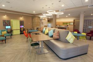 Home2 Suites By Hilton Nampa في نامبا: غرفة انتظار مع أريكة وطاولات وكراسي