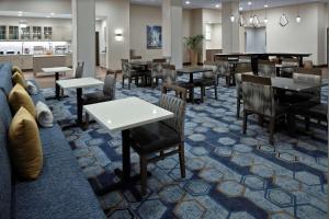 un restaurante con mesas y sillas y un sofá en Homewood Suites By Hilton Greensboro Wendover, Nc, en Greensboro