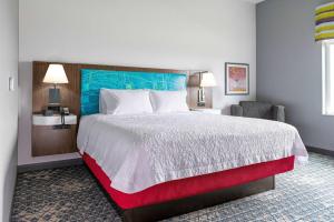 um quarto de hotel com uma cama grande e uma cadeira em Hampton Inn & Suites Pittsburgh New Stanton PA em New Stanton