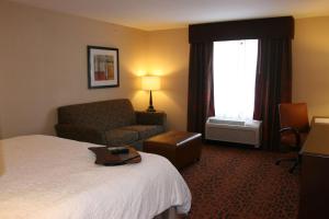 a hotel room with a bed and a chair and a window at Hampton Inn and Suites Peru in Peru +6 photos