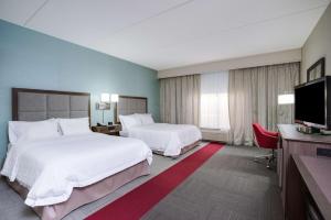 a hotel room with two beds and a flat screen tv at Hampton Inn Middletown in Middletown