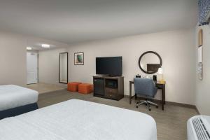 a hotel room with a bed and a desk with a television at Hampton Inn Augusta in Augusta