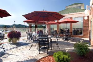 a patio with tables and chairs with red umbrellas at Hilton Garden Inn Clarksburg in Clarksburg