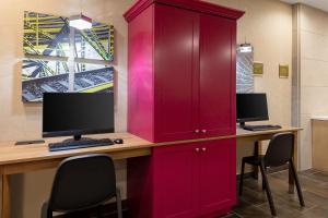 einem roten Schrank mit einem Schreibtisch mit zwei Monitoren in der Unterkunft Home2 Suites By Hilton Valdosta, Ga in Valdosta
