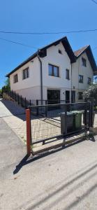 a fence in front of a white house at Family apartment with garden in Sarajevo