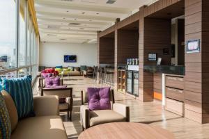 un salón con sillas moradas, mesas y ventanas en Hampton By Hilton Bucaramanga, en Bucaramanga