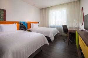 a hotel room with two beds and a desk at Hampton By Hilton Bucaramanga in Bucaramanga