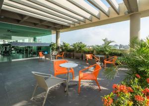 eine Terrasse mit orangefarbenen Stühlen und Tischen auf einem Gebäude in der Unterkunft Hampton by Hilton Barranquilla in Barranquilla