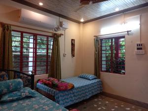 um quarto com 2 camas e uma janela em Atmaja The Cottage Garden Home Stay Malda Under Tourism Department Government of West Bengal em Māldah