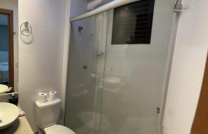 uma casa de banho com um WC e uma cabina de duche em vidro. em Flat Espetacular no Flamboyant em Goiânia