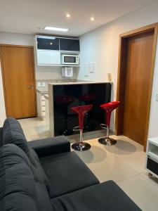 uma sala de estar com um sofá preto e bancos vermelhos em Flat Espetacular no Flamboyant em Goiânia