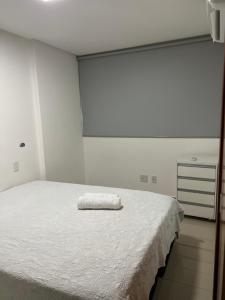 a white bed with a white towel on top of it at Flat Espetacular no Flamboyant in Goiânia