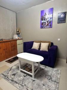 Cozy studio apartment في دار السلام: غرفة معيشة مع أريكة زرقاء وطاولة بيضاء