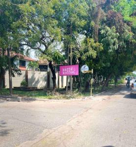 a sign on the side of a street with trees at Cozy studio apartment in Dar es Salaam
