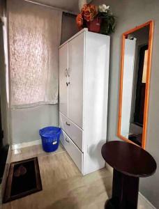a white cabinet in a room with a table and a stool at Cozy studio apartment in Dar es Salaam