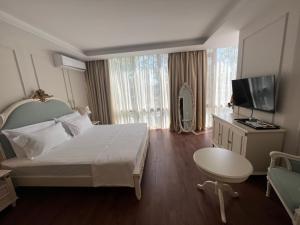 ein Hotelzimmer mit einem großen Bett und einem TV in der Unterkunft SOL INVICTUS Boutique Hotel Durres Albania in Durrës