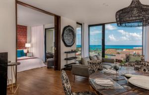 a living room with a couch and a bed and a table at The Fives Downtown Hotel & Residences, Curio Collection by Hilton in Playa del Carmen